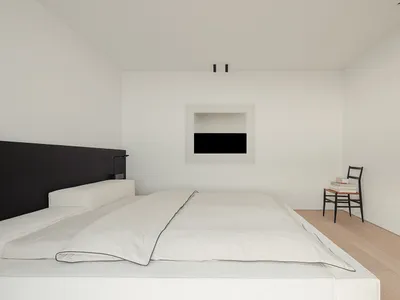 Cozy modern bedroom with a bed, chair, and fireplace, surrounded by natural light and wood accents