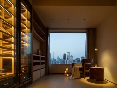 Cozy living room with a large window, a chair, a couch, a dining table, and a vase, set against a city view