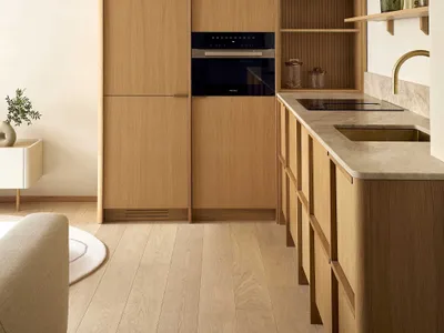 Well-lit kitchen with wooden cabinets, a black oven, and a sink, featuring a modern and functional design with natural materials