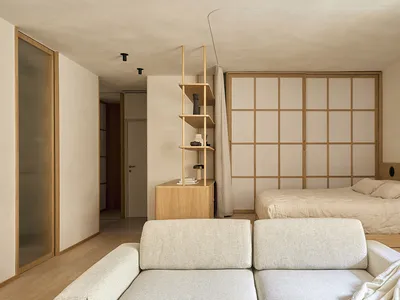 Cozy bedroom with a bed, couch, and bookshelf, featuring wood and fabric materials in a well-lit space