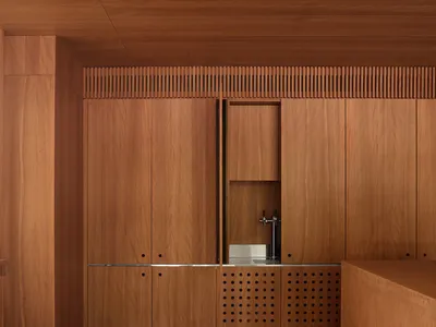 A modern kitchen with wooden cabinets and a sink in a dimly lit space