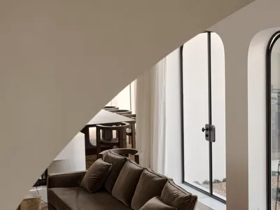 Cozy modern living room with a couch, chair, and dining table, decorated with a potted plant and natural light from the windows