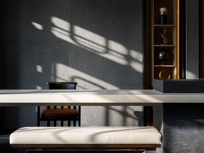 Dining room with a large marble table, black chairs, a couch, and a vase, set in a dimly lit space