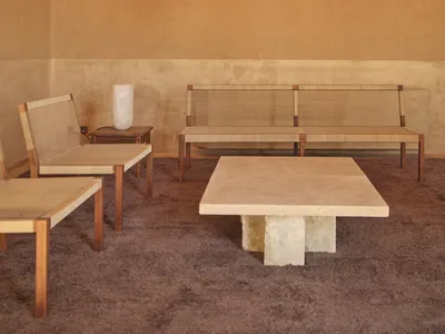 A warm and inviting room with a wooden floor, stone wall, and wooden furniture, including a table and chairs, encouraging social interaction and relaxation