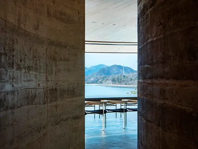 一家現代餐廳的餐桌和椅子，周圍的大型窗戶提供了對外面的水景，自然光線和舒適的氣氛