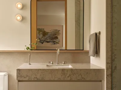 Bathroom with a white color scheme, dim lighting, and a marble sink, mirror, and towel rack
