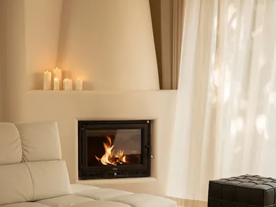 Cozy living room with a white couch and chair in front of a fireplace, surrounded by well-lit space with natural light from windows