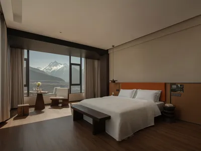 一個有著床、椅子和桌子的舒適房間，具有大窗戶的山景，自然光線創造出溫暖的氣氛