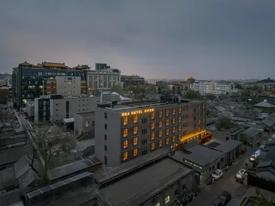 一座城市夜晚的街道，酒店和亮著的招牌，周圍是其他建築物和汽車