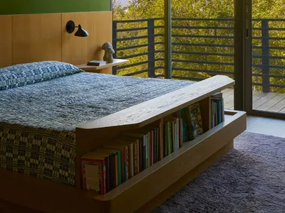 Cozy bedroom with a white bed, a brown bookshelf, and a window above the bed, providing natural light