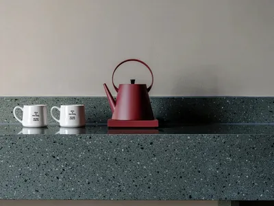 一個紅色茶壺和兩個白色杯子，放在一塊大理石面板上，在一個溫暖且吸引人的空間中