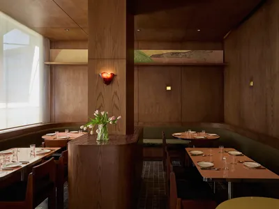 A warm and inviting restaurant dining area with wooden elements, multiple tables, chairs, and soft lighting