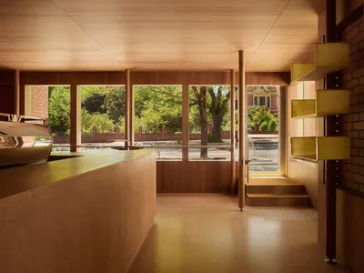 A warm and inviting space with a wooden floor, a counter, a dining table, and chairs, lit by natural light from the windows
