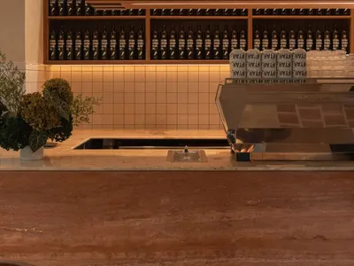 A casual kitchen counter with a wooden surface, featuring a coffee maker and various bottles in a inviting arrangement