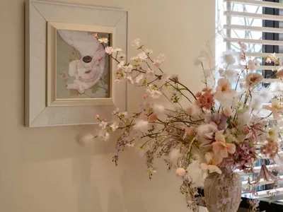 A warm and inviting living room with a couch, chair, and a vase of pink and white flowers on a table, surrounded by soft natural light