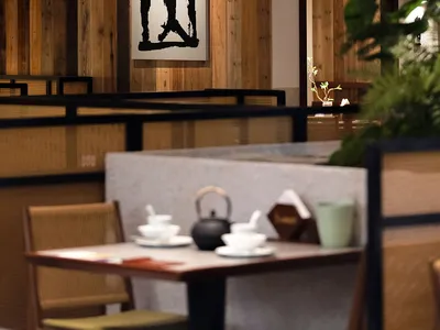 A modern restaurant interior with wooden panel walls, well-lit and inviting, featuring tables and chairs for social dining