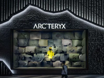 A storefront window display featuring a mannequin in a yellow jacket, surrounded by clothing and merchandise, creating an inviting atmosphere for potential customers