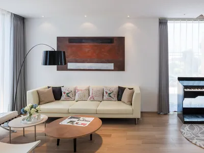 Cozy living room with a brown couch, chair, coffee table, and vase with flowers, set against a dimly lit background with a painting on the wall