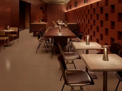 A warm and inviting dining area with a long wooden table surrounded by chairs, set with wine glasses, cups, and a vase, creating a cozy atmosphere