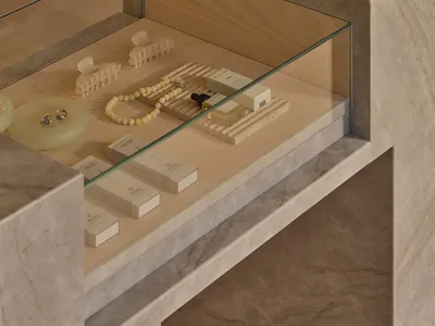 A display case filled with jewelry, cosmetics, and accessories, set against a neutral background, with a focus on the items' beauty and elegance