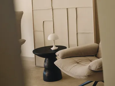 Contemporary living room with a couch, chair, and table, featuring a large abstract painting and neutral colors, with soft and diffused lighting