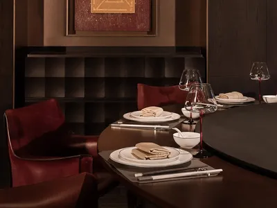 一間餐廳休息室，擺放著一張木頭桌子和椅子，備好餐具，營造出溫暖和親切的氛圍