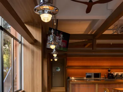 Warm and inviting dining space with wooden tables, chairs, and a TV, surrounded by natural light