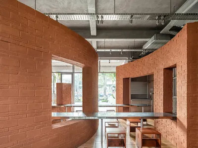 Cozy dining space with a brick wall, a large dining table, and potted plants, surrounded by modern furniture and kitchen area