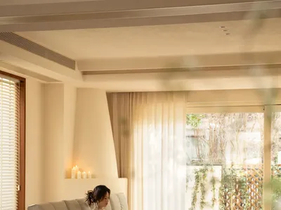一位女性坐在一張白色沙發上，坐在一張椅子和餐桌旁，創造了一個舒適的氛圍