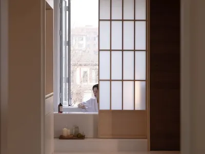 Relaxing bathroom scene with a woman in a bathtub, surrounded by a wooden floor and natural light from a window