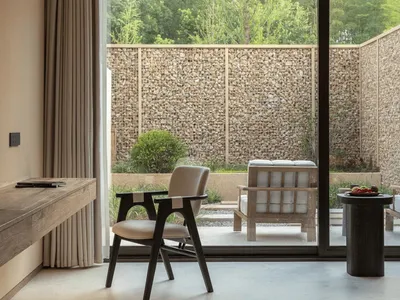 A well-lit living room with a chair, couch, dining table, and TV, featuring wood and glass materials in a modern style