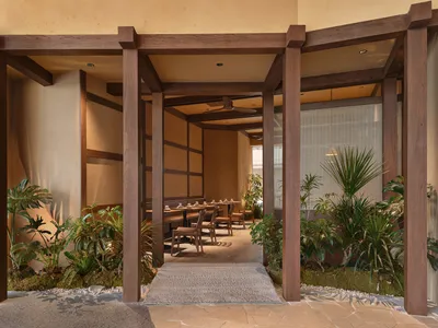 A modern restaurant interior with a wooden floor and ceiling, decorated with potted plants and furnished with chairs and dining tables