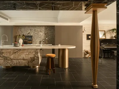 Photograph of a kitchen with a marble countertop, gold barstool, and natural lighting creating a warm and inviting atmosphere