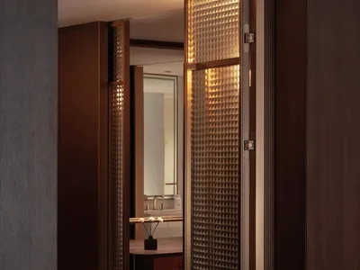 Bathroom with a wooden floor, sink, mirror, and open door, featuring dim lighting and a cozy atmosphere