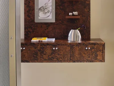 Bathroom with a wooden cabinet, mirror, and picture on the wall, featuring a warm brown and tan color scheme and natural lighting
