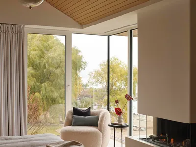 Cozy living room with a white couch, a chair, and a fireplace, decorated with potted plants and a neutral color palette