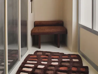 Bathroom with a brown bench, rug, and mirror, featuring a warm and inviting atmosphere with natural lighting