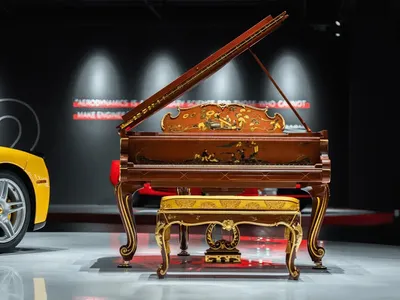 A photograph of a piano in a living space with a hardwood floor, a chair, and a couch in the background, creating an elegant and sophisticated atmosphere