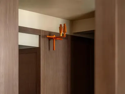 Warm and intimate bathroom with wooden walls, a wooden door, and a wooden cabinet in a brown color scheme, with dim lighting