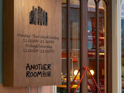 A dimly lit restaurant with modern furniture and a wooden door, creating a cozy atmosphere