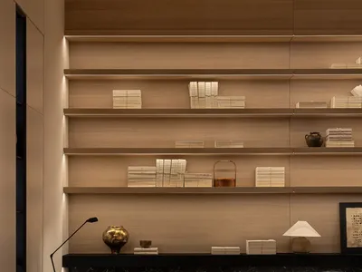 Cozy living room with a wooden floor, a couch, a chair, and a bookshelf with books, creating a warm and inviting atmosphere