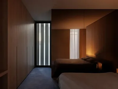 Cozy bedroom with a wooden floor, a bed, a closet, and a window, dimly lit