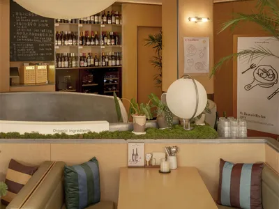 A cozy restaurant dining area with a table and chairs, surrounded by wood and metal elements, dim lighting, and various decorative items