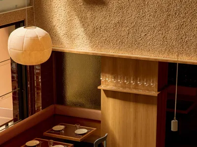 A well-lit restaurant interior with multiple tables, chairs, and wood elements, creating a warm and inviting atmosphere for guests