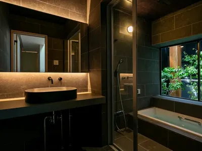 A dimly lit bathroom with a black and white bathtub, sink, and mirror, creating a moody and elegant atmosphere