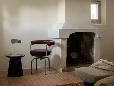 Cozy living room with a white interior, a fireplace, a couch, a chair, and a dining table, creating a warm and inviting atmosphere
