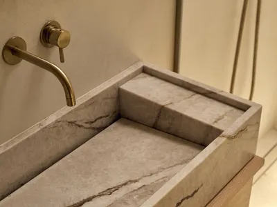 浴室內有大理石 countertop,金屬洗手池,木製櫃子,木地板,以柔光照明