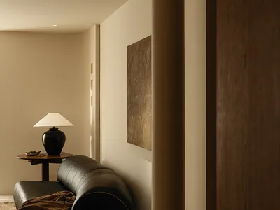 Dimly lit living room with a black couch and a lamp on a nearby table, creating a cozy atmosphere