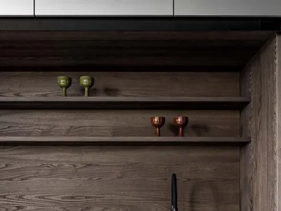 Modern kitchen with wooden cabinets, a black sink, and a wooden countertop, featuring a shelf with glasses and a dimly lit atmosphere