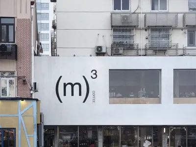 一棟現代飯店白色外牆、黑色招牌、自然光照下充滿亮麗氣氛的外觀照
